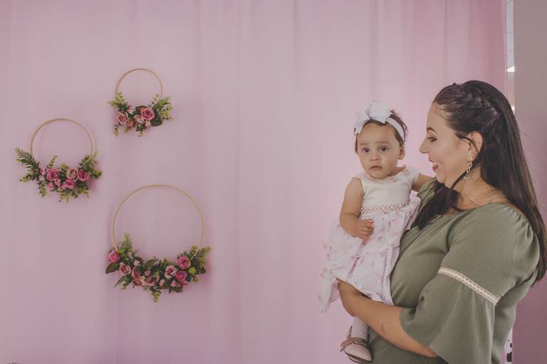 mãe e bebe em aniversário ao lado de arco de flores
