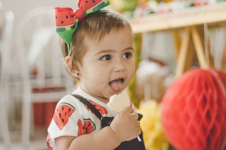 criança vestindo roupa de melancia e comendo doce em festa de frutinhas