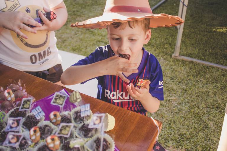 criança comendo brigadeiro em aniversário de super heróis