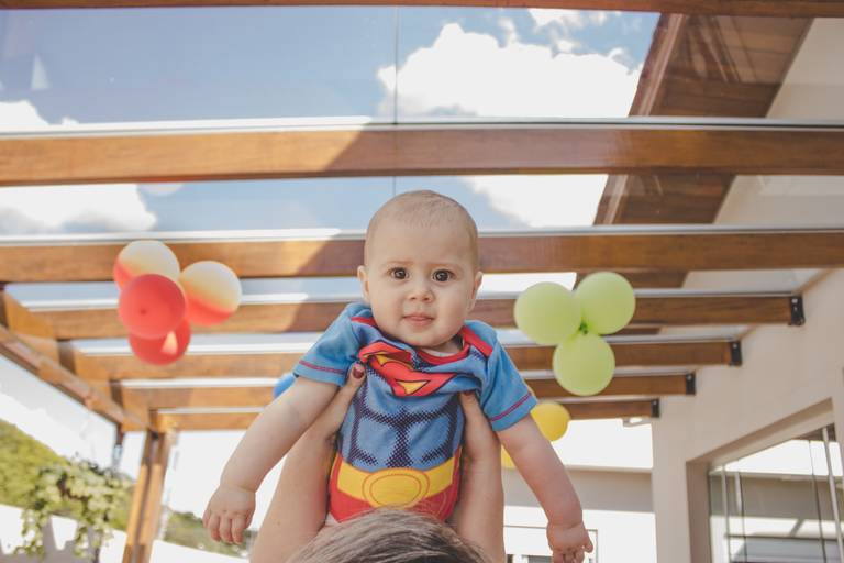 bebe elevado ao alto vestido de super herói