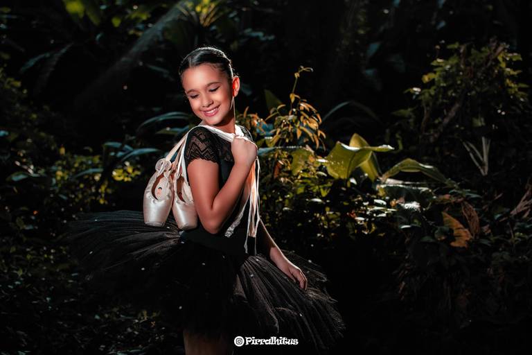 Bailarina segurando sapatilhas nas costas pelas fitas.