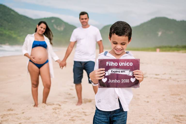 Família na praia, meninino segurando placa que diz: 