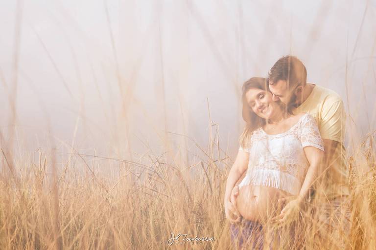 Casal posando na praia com neblina para um lindo ensaio gestante.