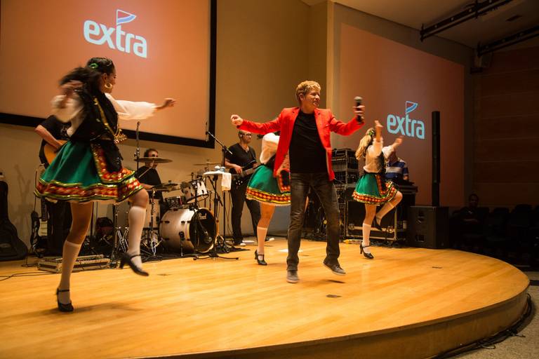 Artista dançando com energia e expressão no palco, com iluminação que destaca sua performance.
