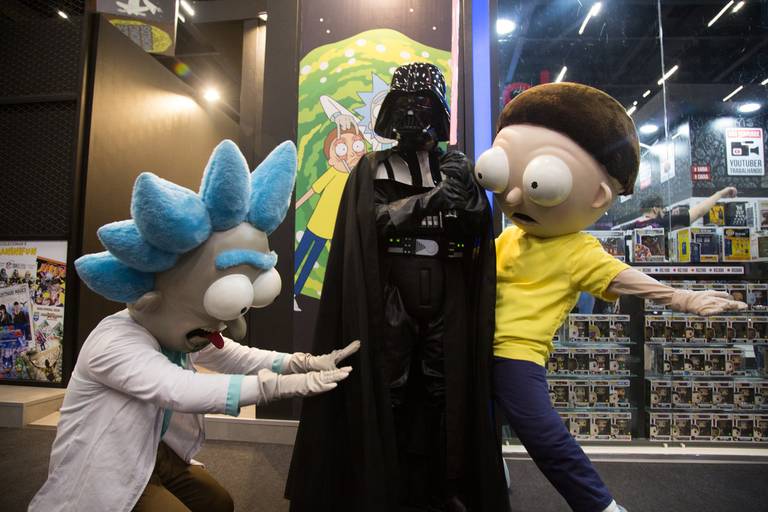 Cosplays de Star Wars e Rick and Morty interagindo em uma feira, combinando diferentes universos da cultura pop.