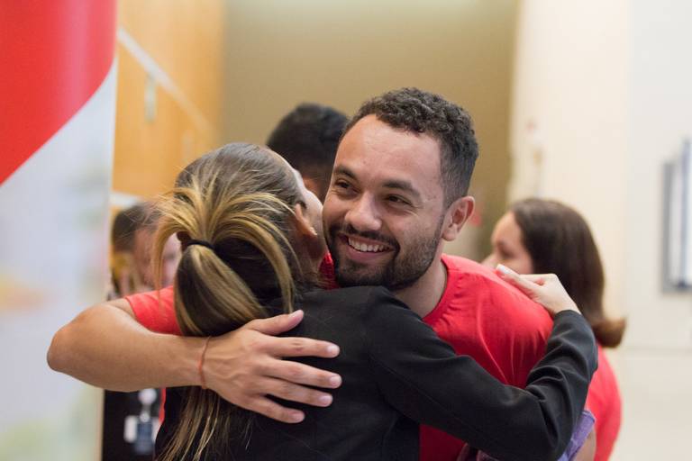 Dois participantes de um evento se abraçando, demonstrando carinho e conexão em um momento de confraternização.