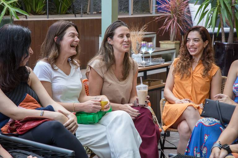 Participantes de um evento rindo e conversando, demonstrando descontração e um bom ambiente de socialização.