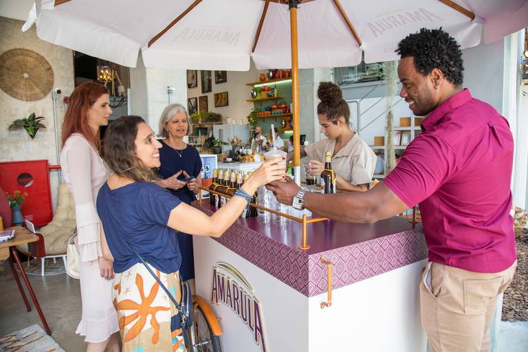 Participantes do evento servindo-se de bebidas em uma barraca ou balcão, em um momento de descontração.