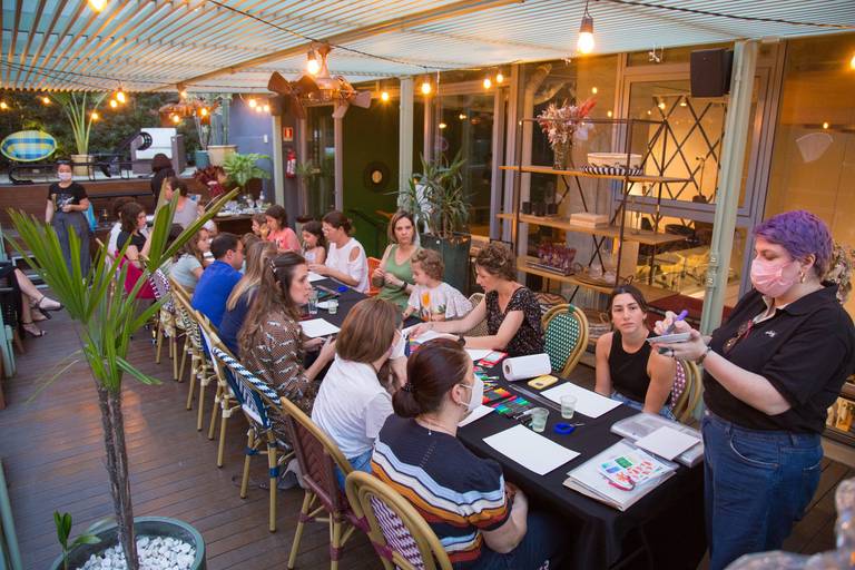 Mesa de participantes de um workshop de desenho, com materiais como papéis e lápis dispostos, indicando a atividade criativa.
