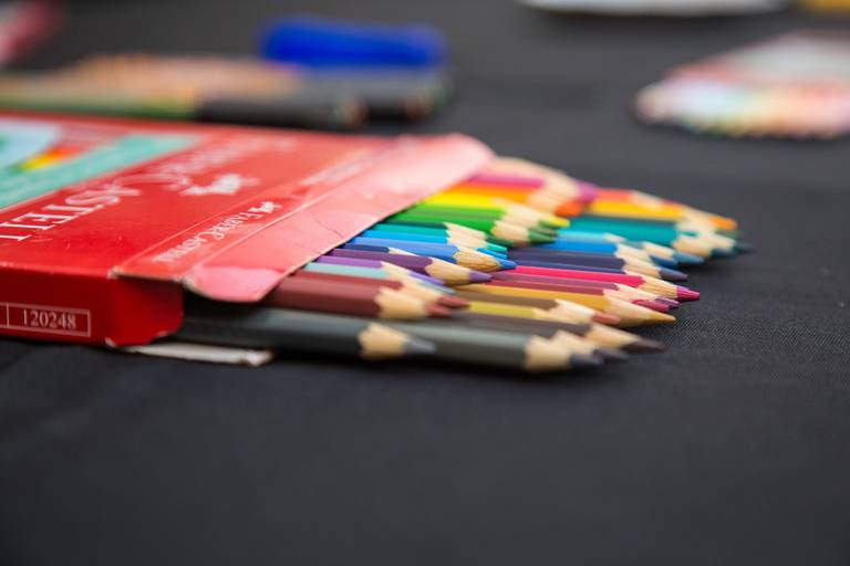 Caixa de lápis de cor vibrante em destaque, com diversas tonalidades, pronta para uso em um workshop de desenho.