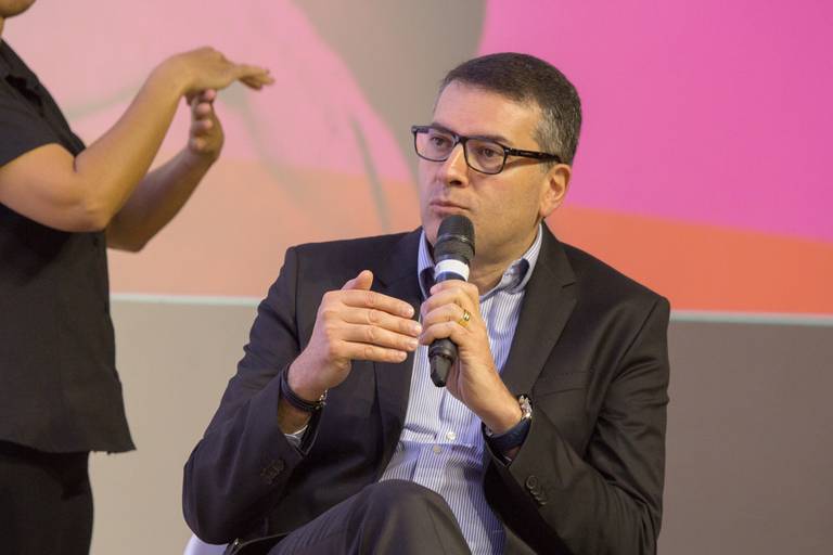 Palestrante em um close-up, com foco em sua expressão e comunicação durante a apresentação.