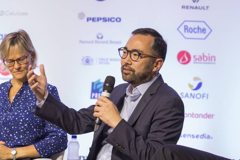 Participante com semblante sério, sentada no palco, abordando um tema importante durante o evento.