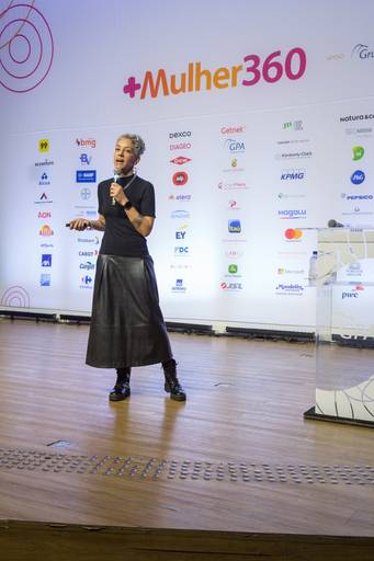 Palestrante com expressão inspiradora no palco, transmitindo paixão pelo tema abordado.