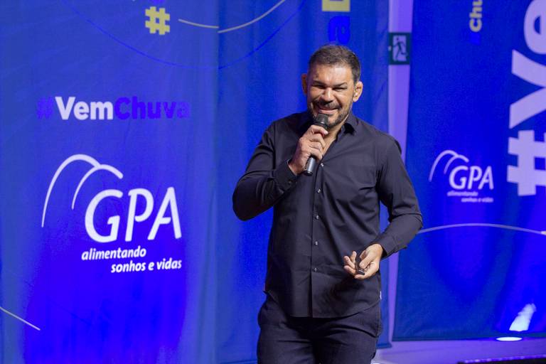 Palestrante com foco na expressão facial, conversando com a audiência em um evento.