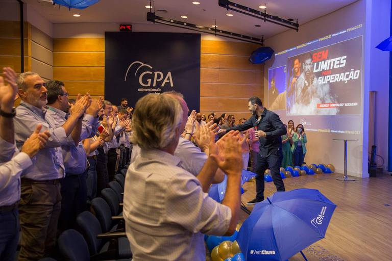 Público em um evento aplaudindo o palestrante com entusiasmo, demonstrando aprovação e apreço.