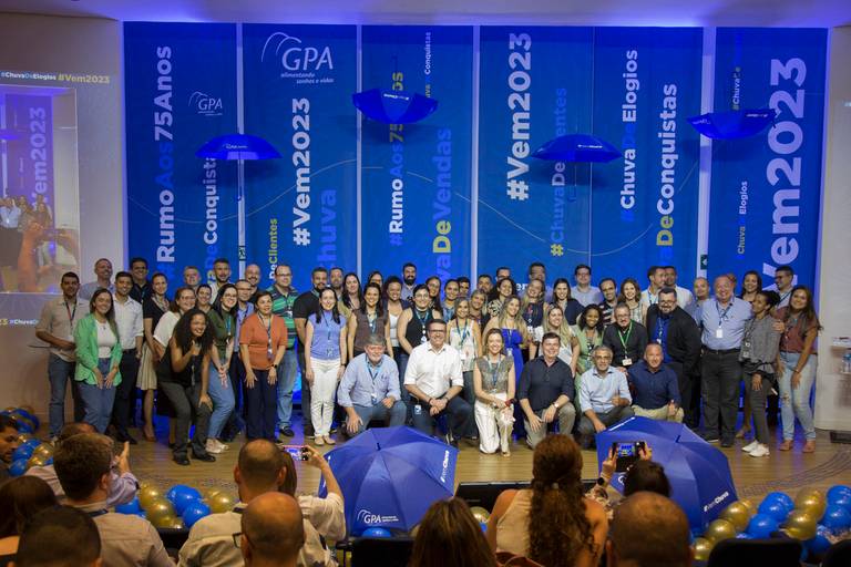 Grupo de pessoas premiadas posando no palco, exibindo seus reconhecimentos em um momento de celebração.