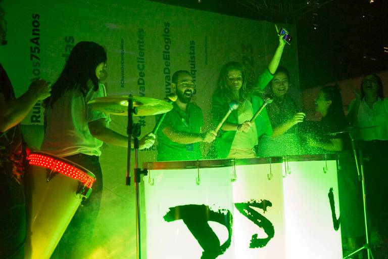 Cena de um show de tambores, com foco nos ritmistas e seus instrumentos, em uma performance vibrante.