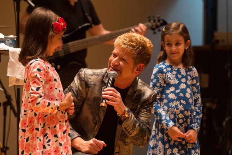 Artista conversando e interagindo com crianças no palco, criando um momento divertido e acolhedor.