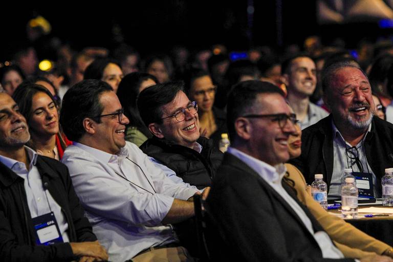 Participantes sorrindo na plateia, desfrutando do evento e demonstrando satisfação.