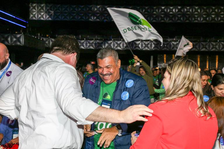 Participantes de um evento conversando e sorrindo, em um momento de interação e descontração.