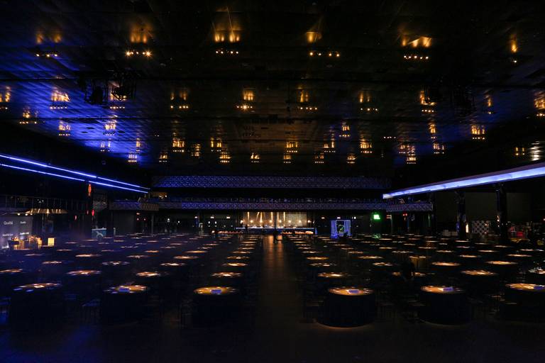 Espaço do evento montado e vazio antes do início, com cadeiras e equipamentos prontos para receber o público.