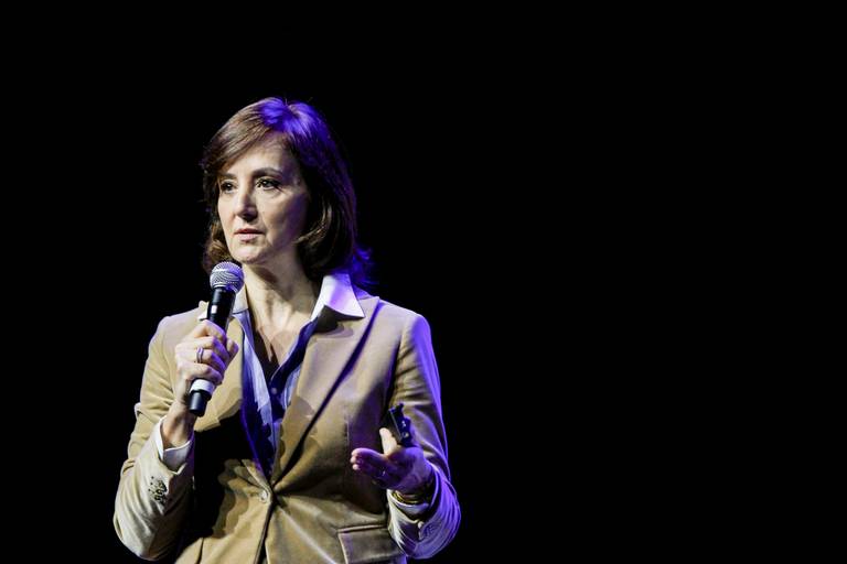 Palestrante em destaque, com postura profissional e expressão engajada durante sua fala em um evento.