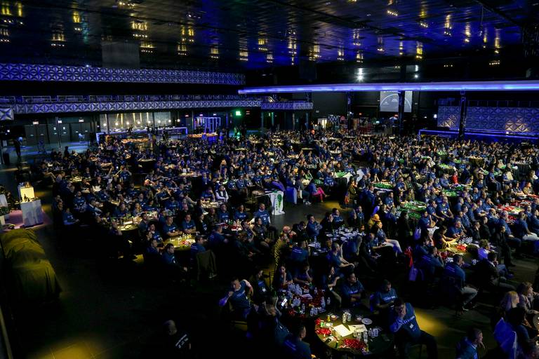 Visão geral de um evento lotado, com a plateia preenchida e a energia do público evidente.