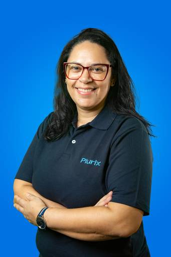 Mulher em retrato corporativo, com semblante sério e postura que denota autoridade em fundo azul.