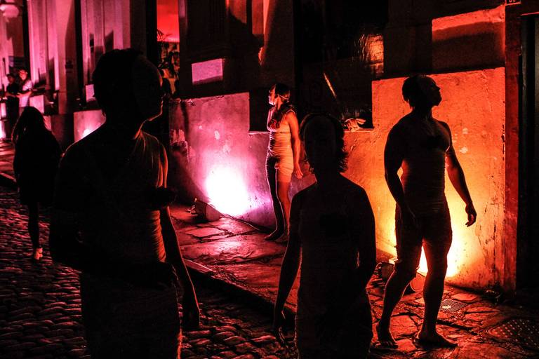 Artistas em silhueta no palco, com luzes coloridas vibrantes ao fundo, criando uma atmosfera visualmente impactante.