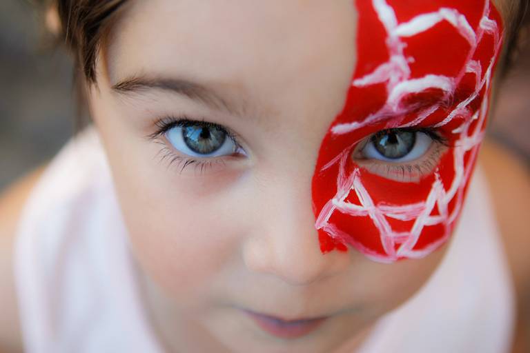 Criança com olhos claros em destaque, com expressão de curiosidade ou encantamento, em um contexto de evento.