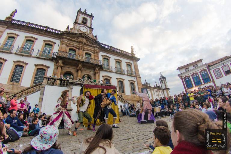 Cenário de um teatro ao céu aberto, com palco e assentos sob o céu, ideal para apresentações culturais.