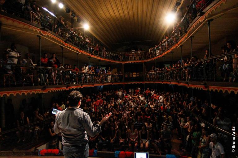 Artista se comunicando com o público, que está ao fundo, em um momento de interação durante uma apresentação.