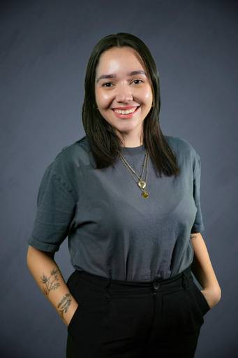 Retrato de uma líder feminina, com expressão ponderada e postura firme em fundo neutro.