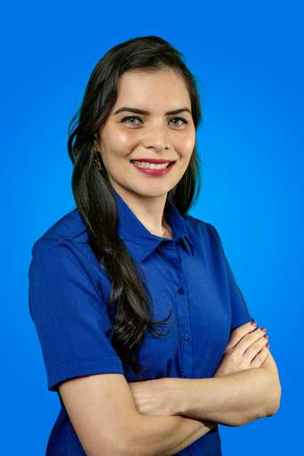 Mulher em retrato corporativo, com semblante sério e postura que denota autoridade em fundo discreto.