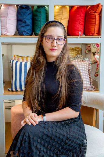 Retrato corporativo feminino em uma poltrona com fundo de almofadas coloridas 