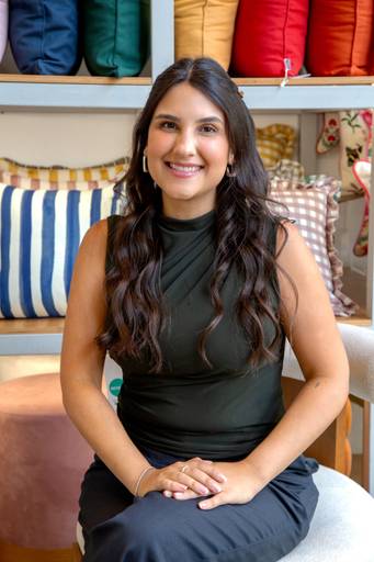 Retrato corporativo feminino em uma poltrona com fundo de almofadas com texturas e cores distintas