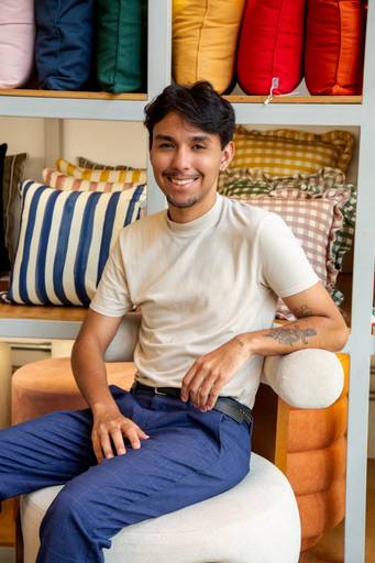 Retrato corporativo masculino em uma poltrona com fundo de almofadas com texturas e cores distintas