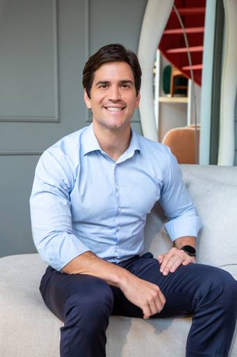 Retrato corporativo masculino em sofá de alto padrão com fundo elegante e um espelho