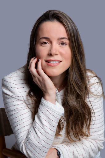 Profissional feminina em retrato, com postura elegante e presença forte em ambiente corporativo com fundo discreto.