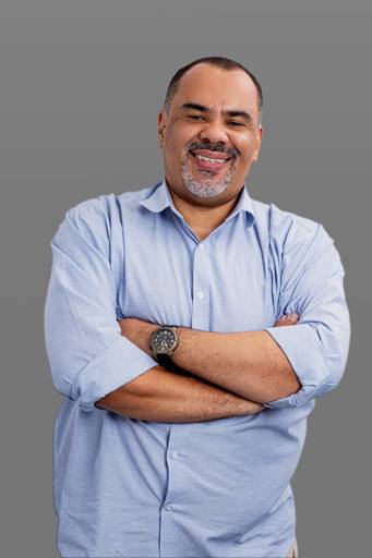 Retrato empresarial de um profissional masculino com fundo neutro cinza, demonstrando postura e autoridade.