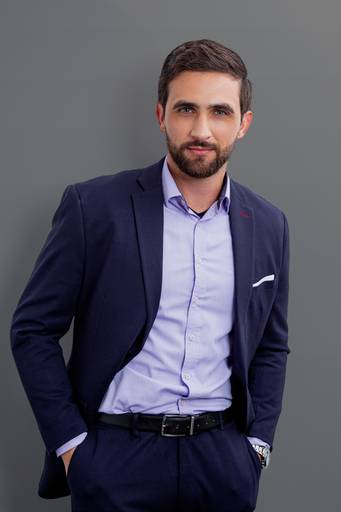 Retrato corporativo de um homem com fundo cinza, transmitindo profissionalismo e seriedade.