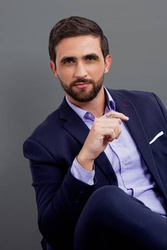 Primeiro plano de um executivo com fundo cinza, com um leve sorriso que denota acessibilidade e profissionalismo.