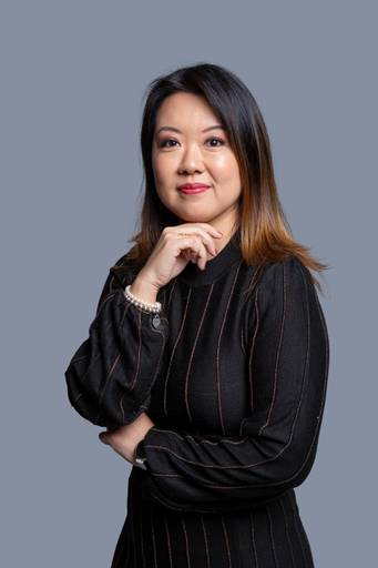 Mulher em retrato de negócios, com olhar analítico e postura profissional em fundo neutro.