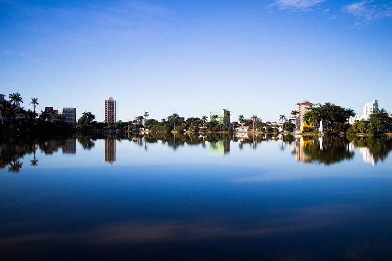 Lago em Sete Lagoas, Minas Gerais, espelhando a silhueta da cidade na água calma, criando um reflexo.