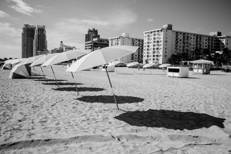 Fotografia em preto e branco de guarda-sóis dispostos em perspectiva em uma praia de Miami, EUA.