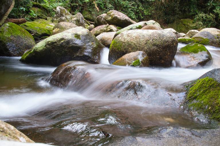 Água de rio em efeito seda, com longa exposição, fluindo sobre pedras em Ilhabela, São Paulo.