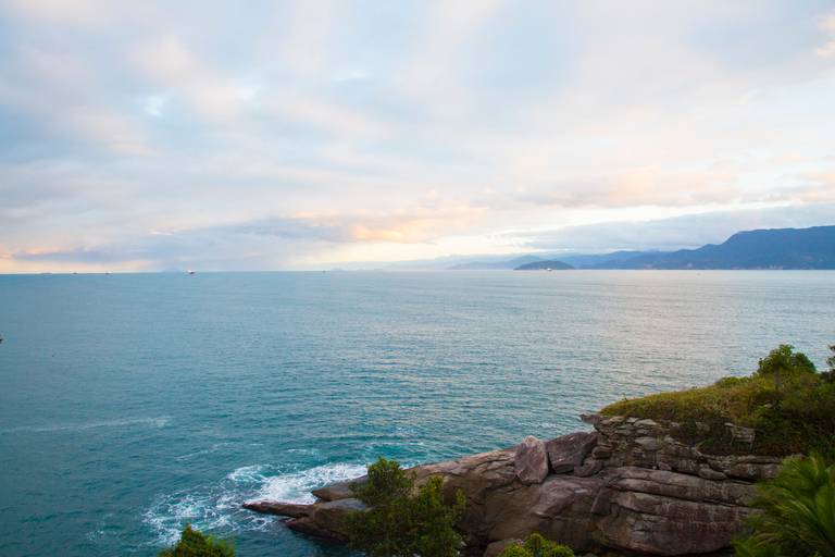 Vista da costa de Ilhabela, São Paulo, com a linha do horizonte, o mar e a vegetação costeira.