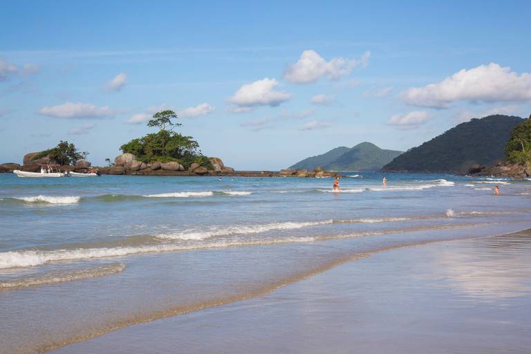 Praia de Castelhanos em Ilhabela, São Paulo, com areia clara, mar azul e vegetação exuberante.