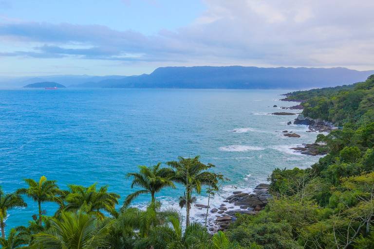 Vista panorâmica da costa de Ilhabela, São Paulo, com o mar azul e a vegetação exuberante.