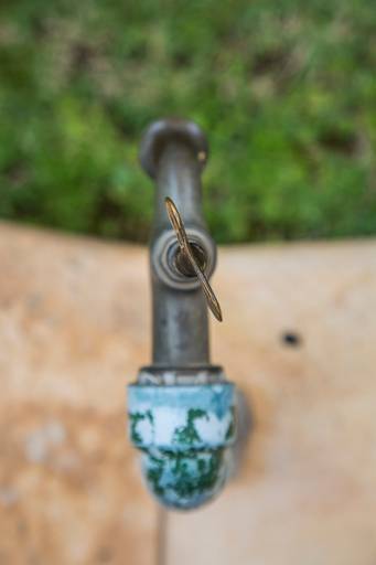 Vista artística de cima de uma torneira de metal, com gotas de água ou reflexos.